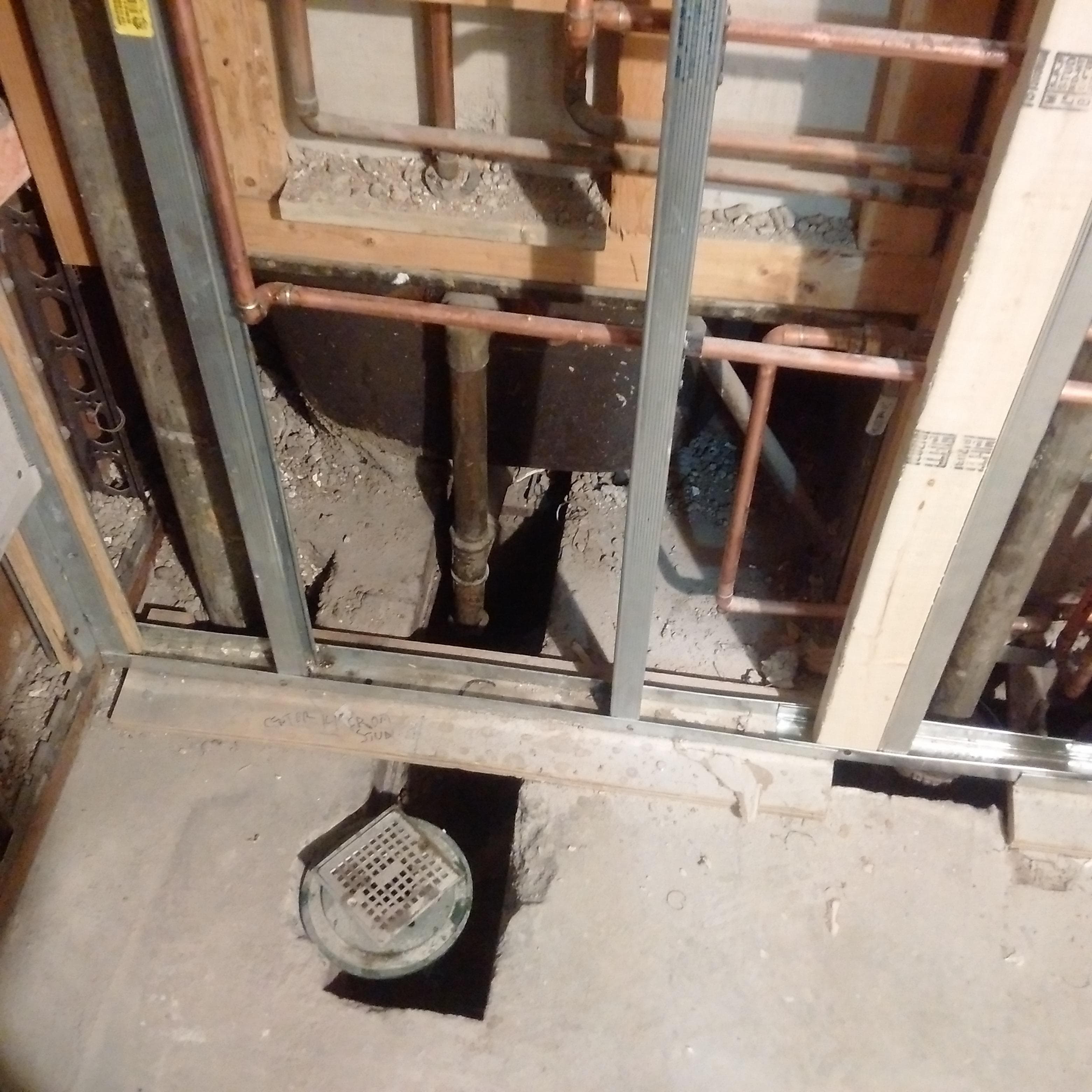 Bathroom rough-in plumbing with copper piping and floor drain installation
