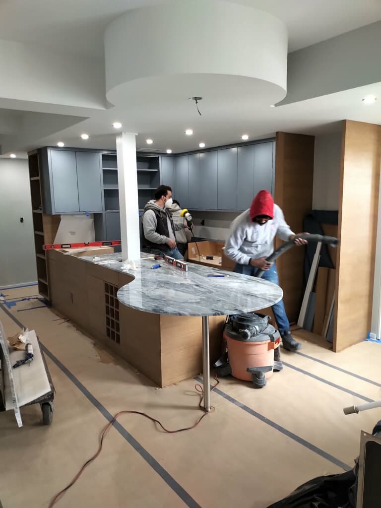Kitchen island with marble countertop and modern gray cabinetry installation in progress